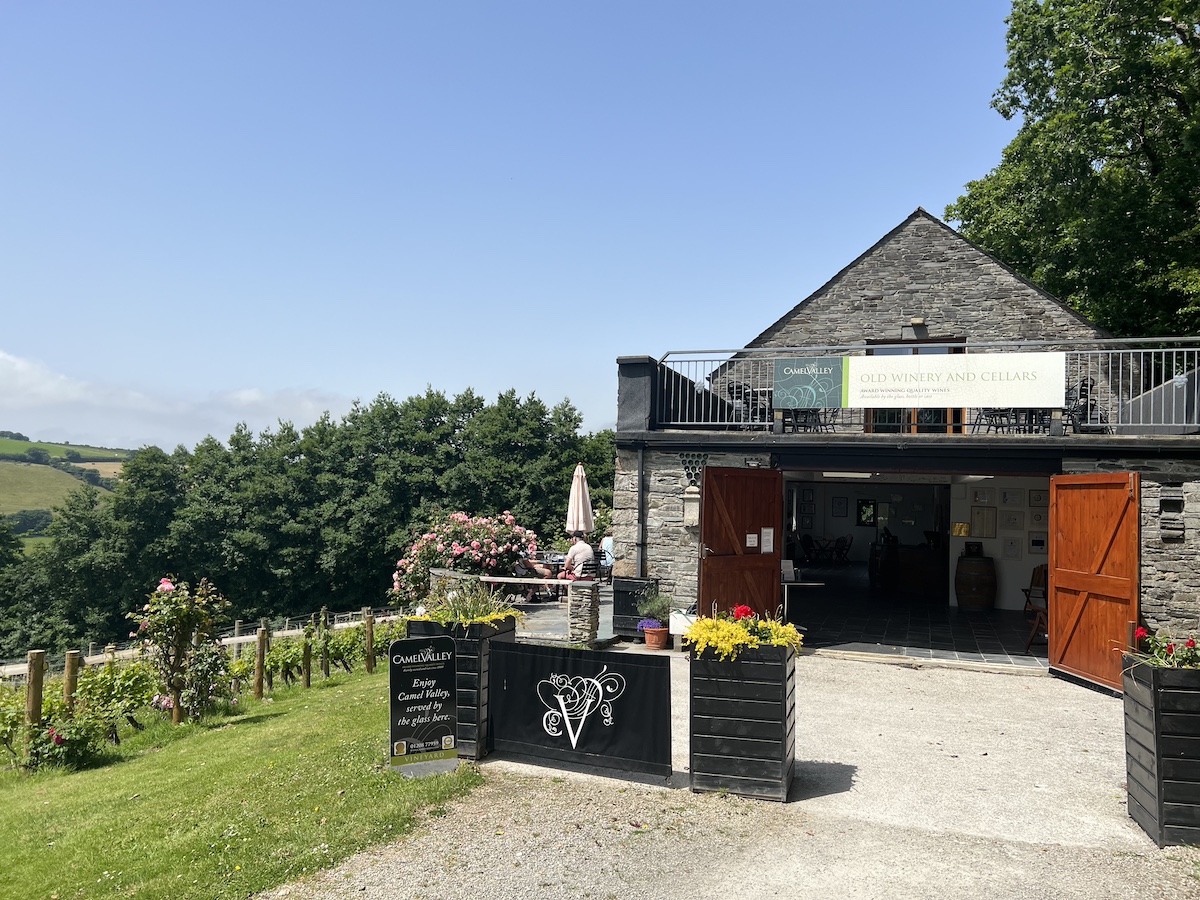Stone-built winery and cellar building with wooden planters and vines