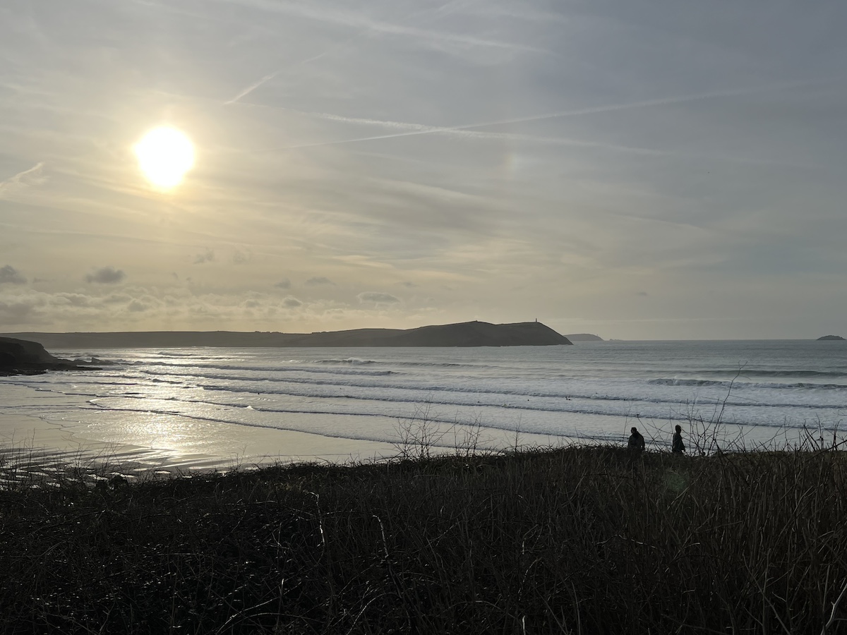 Sunset over a beach with cliffs in the foreground and background