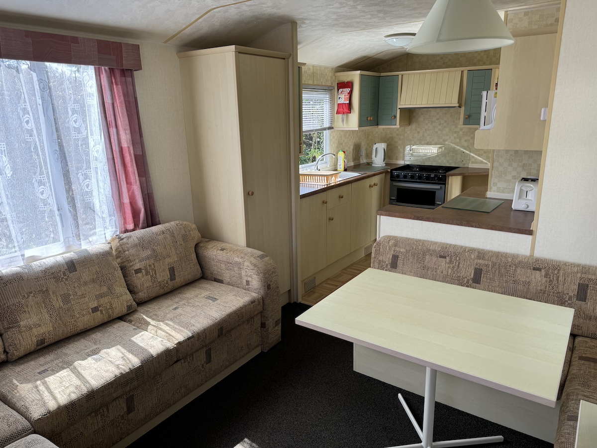Caravan living room and kitchen with settees, table, kitchen units, sink and cooker