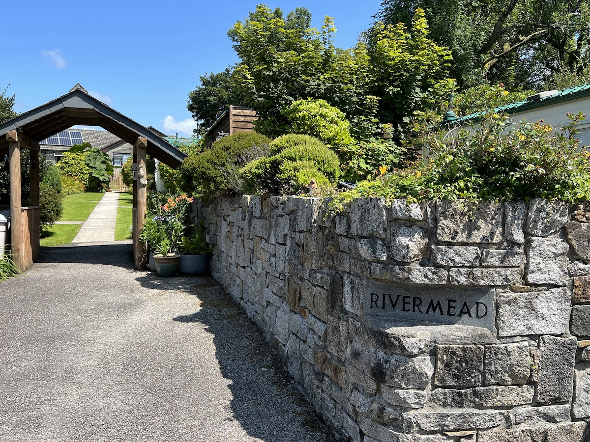 Stone wall with 'Rivermead' sign and wooden archway