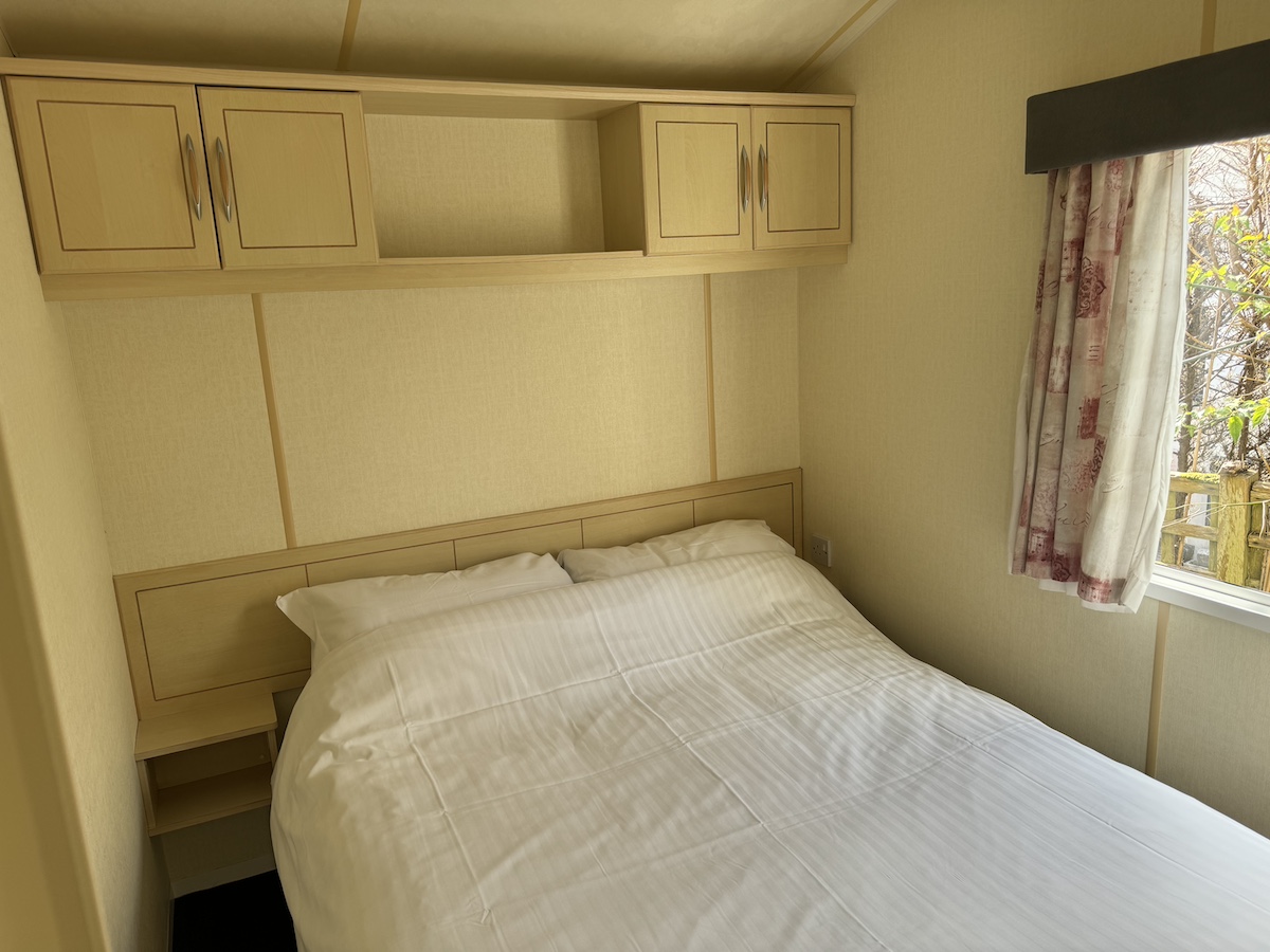 Caravan bedroom with double bed, side tables and overhead cupboards