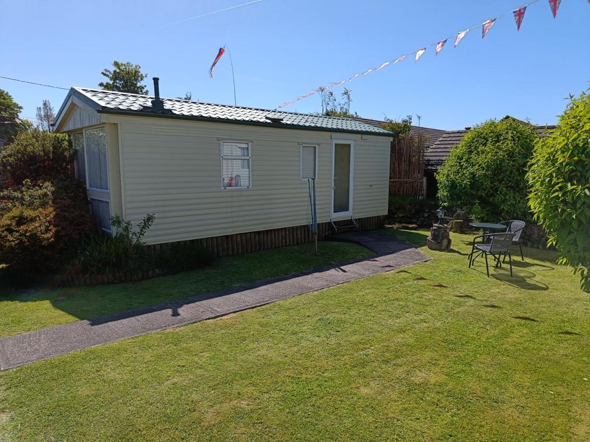 Cream caravan with large grass area, bushes and garden table and chairs