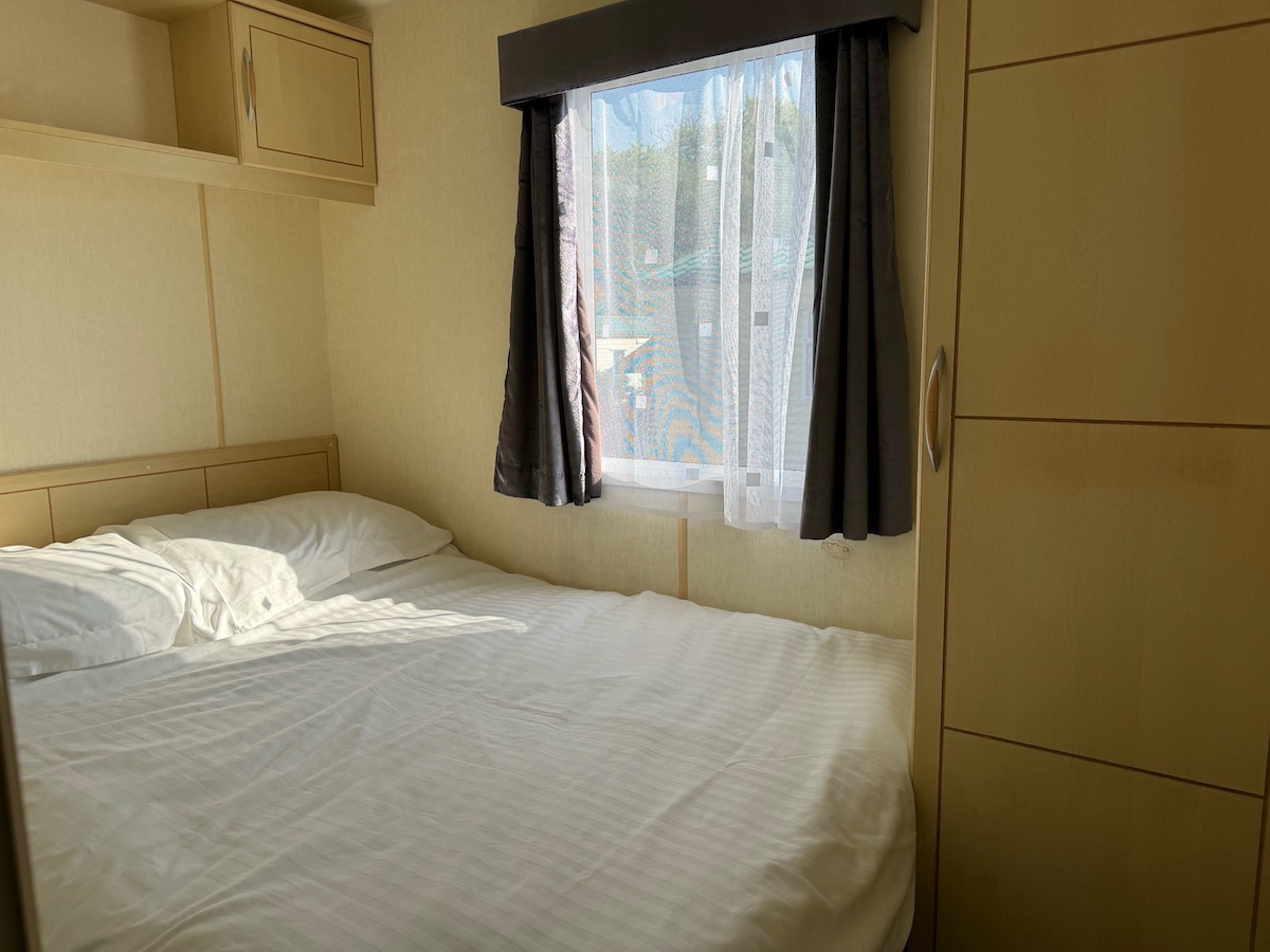 Caravan bedroom with double bed, wardrobe and overhead cupboards