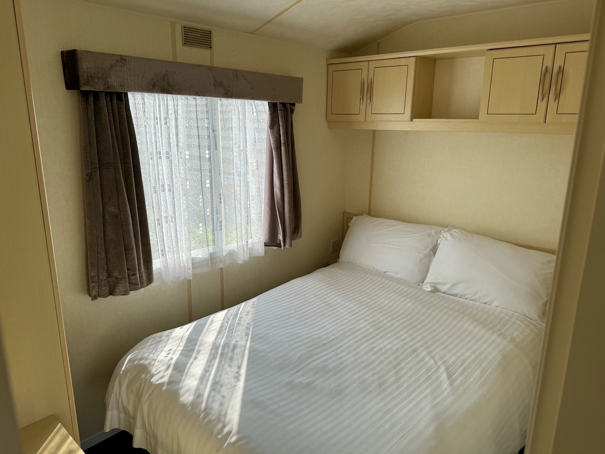 Caravan bedroom with double bed and overhead cupboards