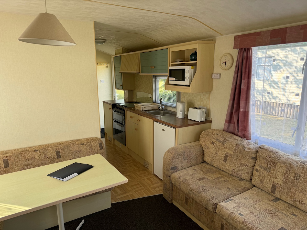 Caravan living room with settees, table and kitchen area